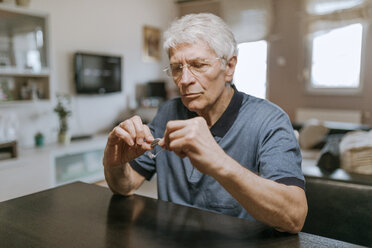 Senior man examining hearing aid - ZEDF00750