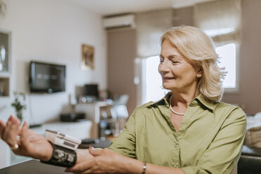 Lächelnde Seniorin beim Blutdruckmessen - ZEDF00753