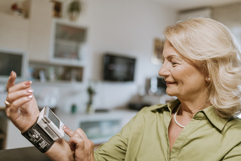 Smiling senior woman taking her blood pressure stock photo