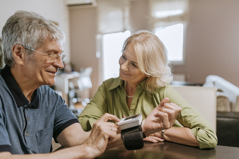 Smiling senior couple taking blood pressure stock photo