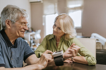Lächelndes Seniorenpaar beim Blutdruckmessen - ZEDF00756