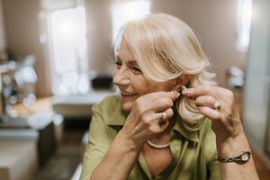 Senior woman applying hearing aid - ZEDF00758