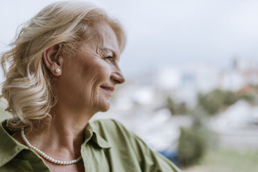 Smiling senior woman with hearing aid outdoors - ZEDF00766