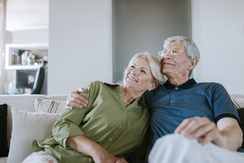 Lächelndes älteres Paar sitzt zu Hause auf der Couch - ZEDF00773