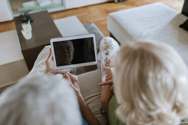 Älteres Paar sitzt zu Hause auf der Couch und teilt sich ein Tablet - ZEDF00779