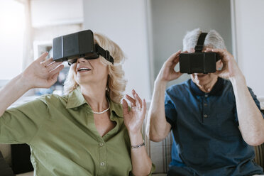 Senior couple at home sitting on couch wearing VR glasses - ZEDF00782