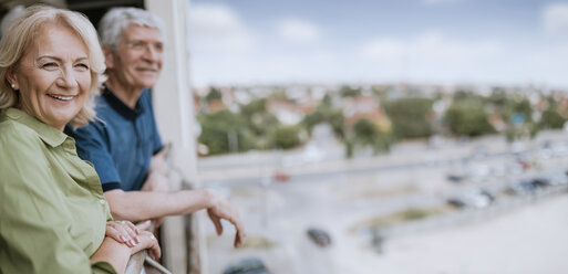 Lächelndes älteres Paar auf dem Balkon mit Blick auf die Aussicht - ZEDF00792