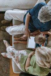 Großeltern und Enkel zu Hause auf der Couch sitzend und mit Tablet - ZEDF00799