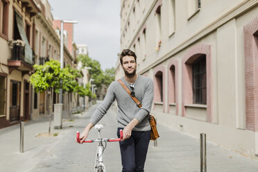 Junger Mann, der sein Fahrrad schiebt - GIOF02961