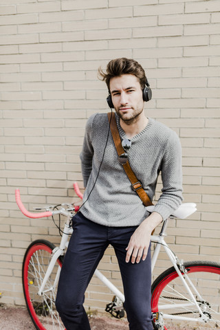 Porträt eines jungen Mannes mit Rennrad und Kopfhörern, lizenzfreies Stockfoto