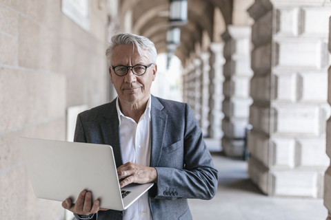 Porträt eines älteren Geschäftsmannes mit Laptop, lizenzfreies Stockfoto