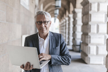 Portrait of senior businessman holding laptop - GUSF00060