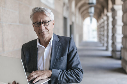 Portrait of senior businessman holding laptop - GUSF00061