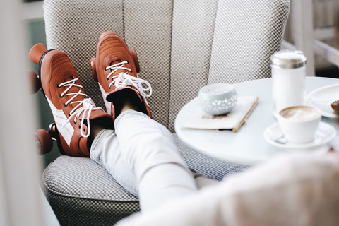 Frau in Rollschuhen in einem Café sitzend, Beine hochgelegt, lizenzfreies Stockfoto