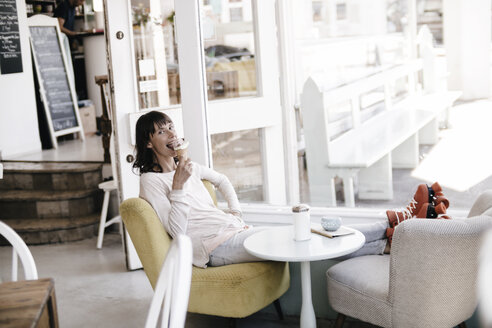 Frau in Rollschuhen sitzt in einem Café und isst ein Eis - KNSF01865