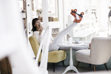 Woman wearing roller skates sitting in a cafe, eating icecream - KNSF01866