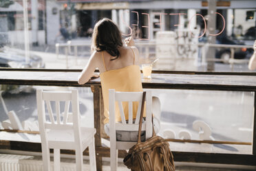 Frau sitzt in einem Café und schreibt das Wort 