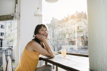 Frau sitzt im Café und malt mit Lippenstift ein Herz auf die Fensterscheibe - KNSF01881