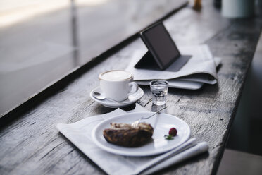 Kuchen, Kaffee und Tablet-PC auf einem Regal in einem Cafe - KNSF01890