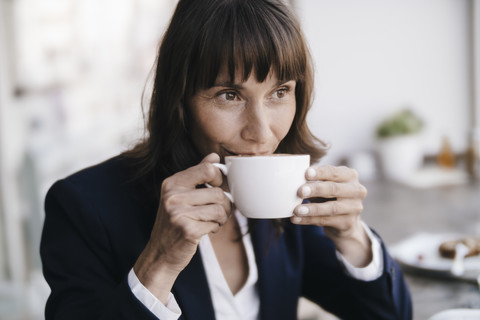 Geschäftsfrau sitzt im Café und trinkt Kaffee, lizenzfreies Stockfoto