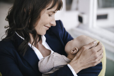 Businesswoman in cafe holding sleeping baby - KNSF01895