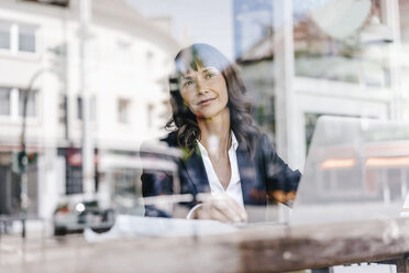 Businesswoman sitting in cafe, daydreaming - KNSF01903