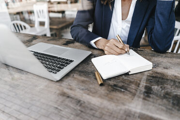 Geschäftsfrau arbeitet in einem Café und schreibt in ein Notizbuch - KNSF01905