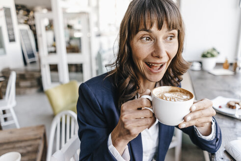 Businesswoman sitting in cafe, drinking coffee - KNSF01909