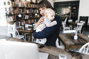 Businesswoman in cafe holding baby - KNSF01912