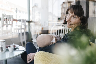 Businesswoman in cafe holding sleeping baby - KNSF01916