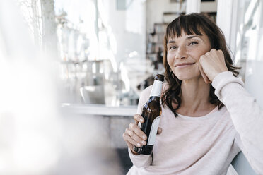 Frau sitzt in einem Café und trinkt Bier - KNSF01925