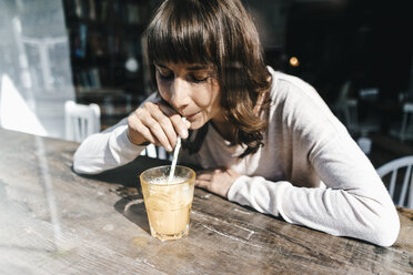 Woman sitting cafe, drinking drink with a straw - KNSF01926