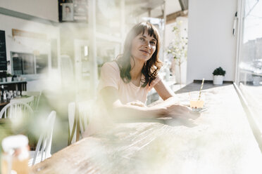 Woman sitting cafe, holding smartphone - KNSF01927