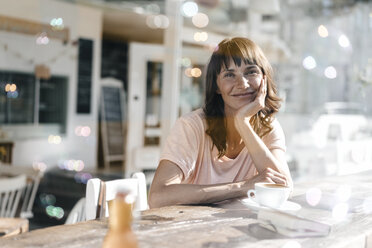 Frau sitzt in einem Café und beobachtet Seifenblasen - KNSF01932