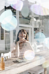Frau sitzt in einem Café und beobachtet Seifenblasen - KNSF01934