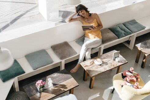 Frau mit Rollschuhen in einem Café sitzend, mit Tablet-PC - KNSF01936