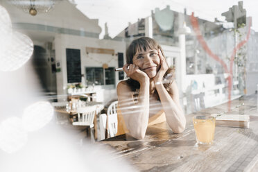 Frau sitzt im Café und malt mit Lippenstift ein Herz auf die Fensterscheibe - KNSF01944