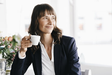 Businesswoman sitting in cafe, drinking coffee - KNSF01947