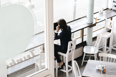 Geschäftsfrau in einem Café, mit Smartphone und Laptop - KNSF01952