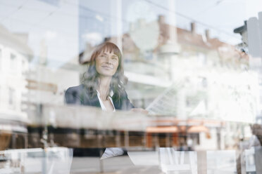 Businesswoman sitting cafe, reading newspaper - KNSF01960