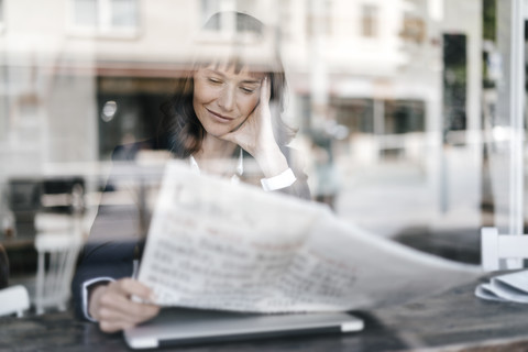 Geschäftsfrau sitzt in einem Café und liest Zeitung, lizenzfreies Stockfoto