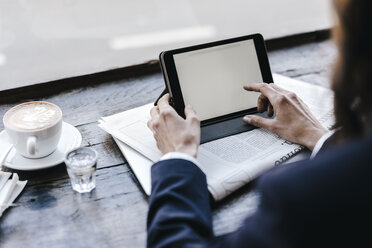 Businesswoman using digital tablet in a cafe - KNSF01963