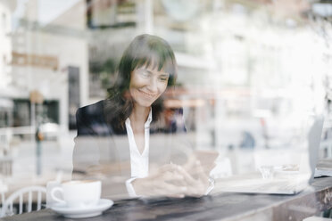 Geschäftsfrau sitzt im Café und benutzt ihr Smartphone - KNSF01971