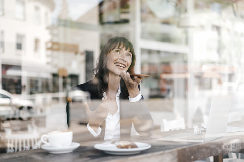 Geschäftsfrau sitzt im Café und benutzt ihr Smartphone, lizenzfreies Stockfoto