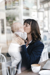 Businesswoman in cafe kissing her baby - KNSF01974