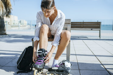Junge Frau beim Anziehen der Inline-Skates - KIJF01633