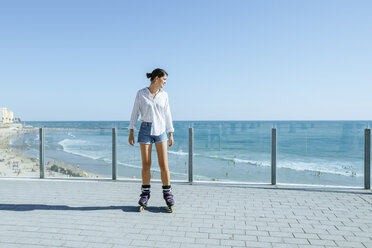 Junge Frau beim Inlineskaten auf der Strandpromenade an der Küste - KIJF01636