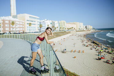 Junge Frau auf Inline-Skates mit Blick auf den Strand - KIJF01642