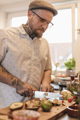 Tätowierter Mann bei der Essenszubereitung in der Küche - GUSF00085