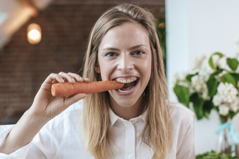 Portrait of young woman biting carrot - GUSF00090